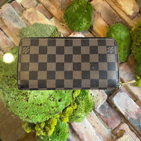 Checkered_wallet_on_a_decorative_surface_with_green_plants