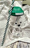 Clear glass with a green Starbucks lid and straw on a white surface