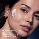 Close-up of a woman's face with cosmetic product on her cheek, against a dark background.