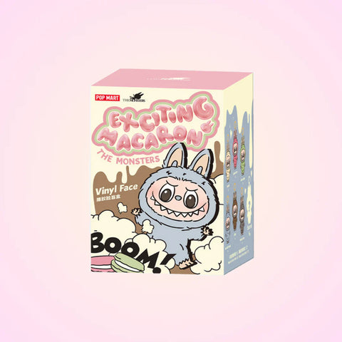Box of 'Exciting Macaron Monsters' vinyl figures with a cartoon character on a pink background