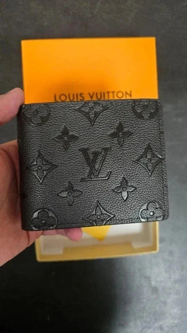 Louis_Vuitton_wallet_held_in_front_of_a_yellow_box_with_Louis_Vuitton_branding.
