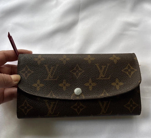 Louis_Vuitton_wallet_with_monogram_pattern_held_by_a_hand_on_a_white_background