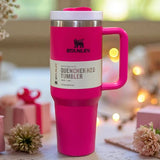 Pink Stanley Quencher H2O tumbler on a decorative surface with blurred lights and flowers in the background