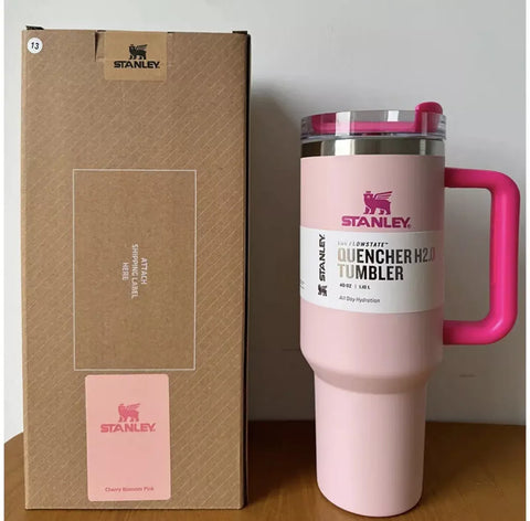 Pink Stanley tumbler with a matching box on a wooden surface.