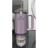 Pink Stanley tumbler with handle on a reflective surface