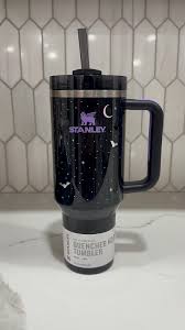 Black insulated tumbler with a design on a white surface