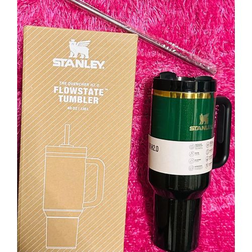 Stanley travel mug with packaging on a pink textured background