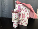 Stanley tumbler with floral design next to a matching pink and white floral box on a dark surface.